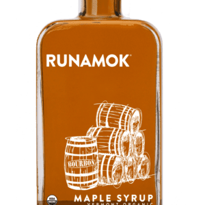 A bottle of maple syrup with some barrels on the side.