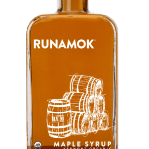 A bottle of maple syrup with some barrels on the side.