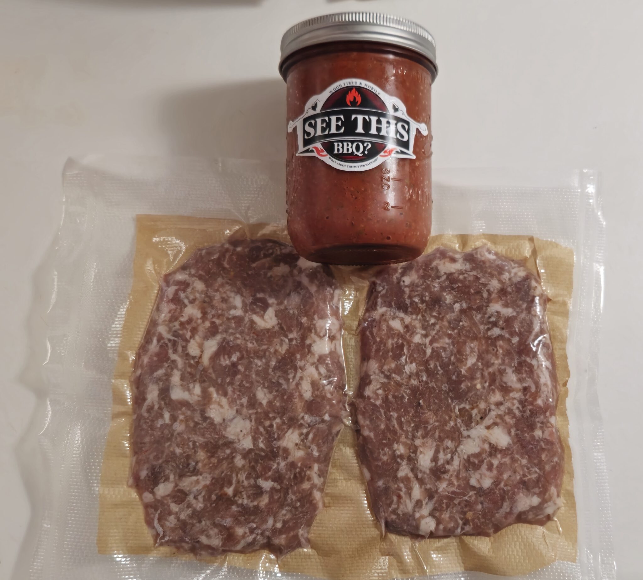 Packaged meat and jar of BBQ sauce.